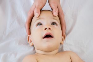 Hands of a mother touching head of her baby boy at home